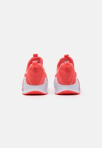 Pantofi sport corali cu un exterior din plasă, talpă texturată albă și mânere la călcâi pentru o îmbrăcare ușoară. Design curat, modern.