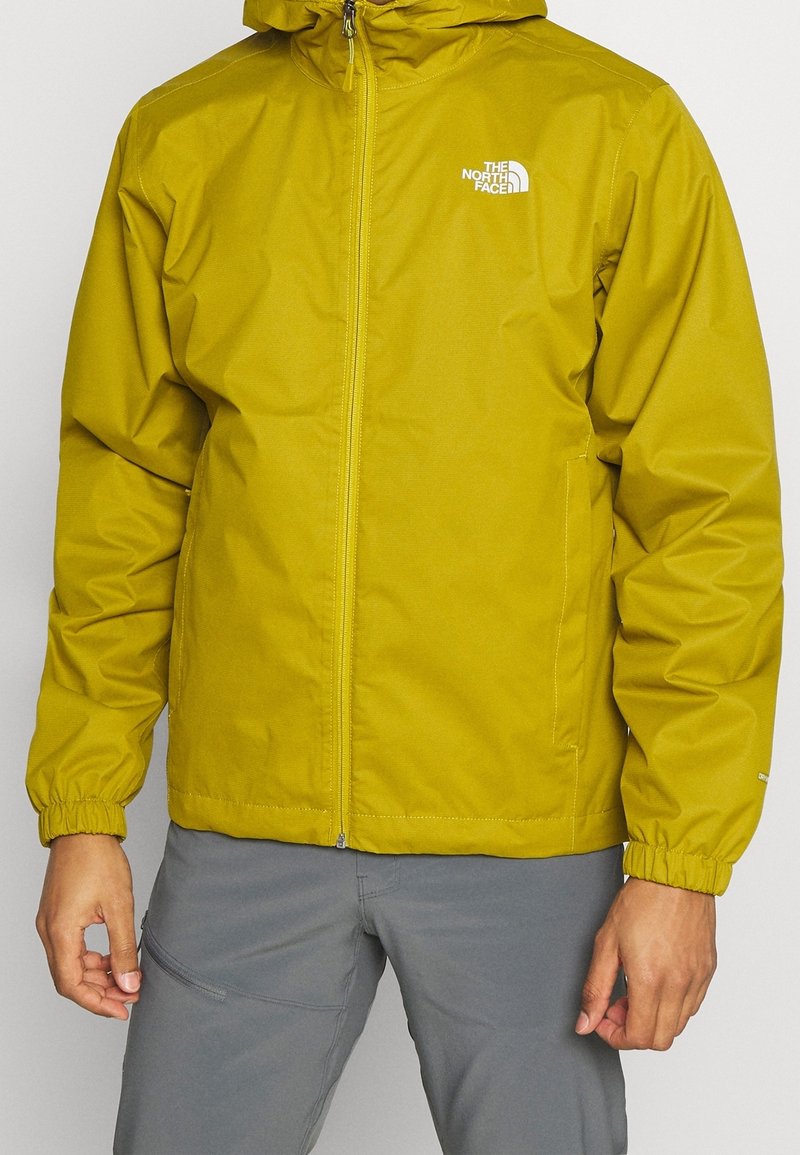 Chaqueta impermeable amarilla con capucha, con puños elásticos y cremallera frontal. Logotipo en el lado izquierdo del pecho, textura suave y corte regular.