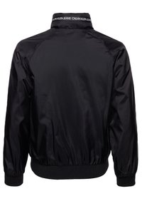 Černá bomber bunda vyrobená z hladkého, lehkého materiálu. Obsahuje elastické manžety a pas, s brandovaným límcem. Jednoduchý design, žádné vzory.