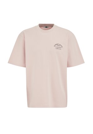 Lichtroze T-shirt met korte mouwen, ronde hals en kleine zwarte tekst "Sunset State of Mind Canggu Afternoon" op de linkerborst.