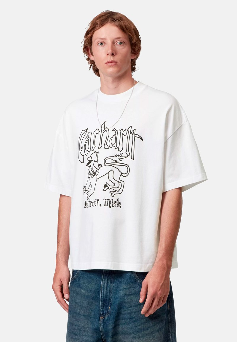 T-shirt bianca in cotone con una grafica nera che presenta la scritta "Carhartt" e un'illustrazione di leone, vestibilità comoda, maniche corte e collo tondo.