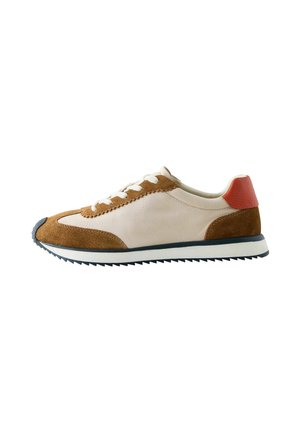 Low-profile sneaker with beige leather and brown suede panels, white laces, a red heel accent, and a ridged black and white sole.