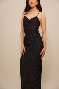 Black spaghetti strap dress with a fitted silhouette, featuring white polka dots, a knotted detail at the bust, and a sleek design.