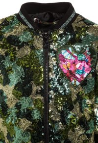 Kurtka bomber wyszywana cekinami w zielono-złotym kamuflażu. Posiada zamek z przodu oraz naszywkę w kształcie serca z kolorowymi motylami.