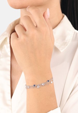 Silberne Kettenarmband mit blauen und klaren Steinen, zartes Design mit mehreren Strängen und unterschiedlichen Platzierungen der Steine.