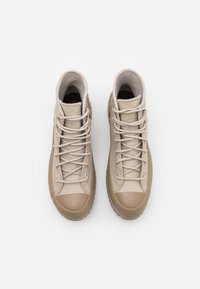 Beżowe trampki za kostkę z fakturowanej skóry, gładkim gumowym noskiem i wyraźnym detalem sznurowania. Miękka wyściółka wewnętrzna.
