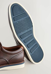 Bruine leren schoen met een gladde afwerking. De zool heeft een blauwe rubberen onderkant met textuurpatronen voor grip en contrasterende witte randen.