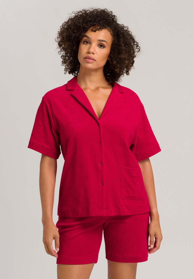 Camisa corta de algodón roja con cuello muesca y bolsillo frontal, combinada con pantalones cortos rojos a juego, ambos con una textura suave.