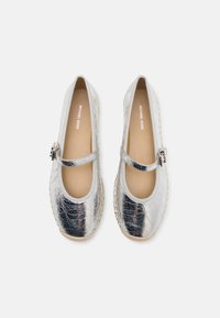Silver metallic ballet flats with a rounded toe, faux leather upper, and a decorative strap with a buckle. Soft beige insole.