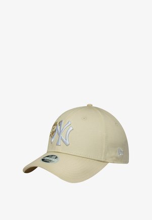 Khaki baseball cap with a curved brim. Features embroidered NY logo in white, gold accents, and eyelets for breathability.
