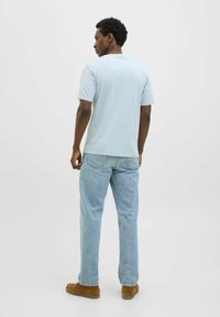 Lichtblauwe t-shirt met korte mouwen, relaxed fit, gemaakt van katoen, gecombineerd met lichte denim jeans en bruine suède schoenen. Eenvoudig ontwerp.