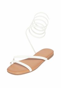 Sandal bianco con cinturini, suola piatta e soletta color sabbia, dotato di un sottile cinturino a spirale attorno alla caviglia per una vestibilità sicura. Materiale liscio, design minimale.