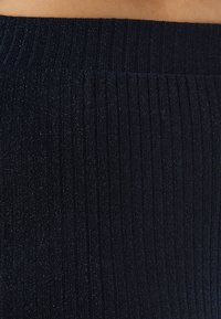 Ribbed navy leggings with a shimmering texture, featuring a wide elastic waistband for comfort and fit. Subtle sparkle throughout the fabric.