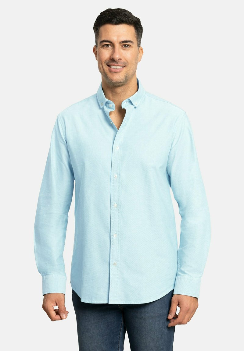 Camisa de botones azul claro con tejido texturizado, mangas largas y cuello clásico. Presenta un dobladillo curvo y botones en contraste.