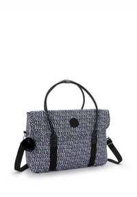 Textured fabric tote bag in navy and white with a wavy pattern. Features black accents, two handles, an adjustable strap, and a pom-pom charm.