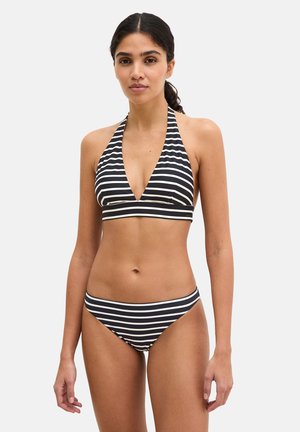 Woman with dark hair in a ponytail wearing a black and white horizontal striped halter bikini with a deep V-neck top and matching bottoms.