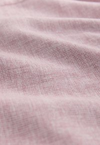 Tissu rose doux avec une texture tissée subtile et des plis délicats créant une surface lisse et ondulée.
