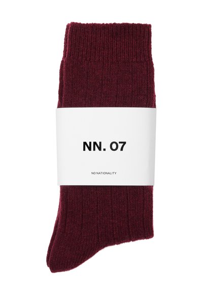 Burgundowe skarpetki prążkowane o miękkiej teksturze, z białym pasem z napisem "NN. 07" oraz "NO NATIONALITY" w pogrubionym czarnym tekście.
