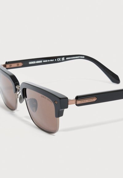 Črna in rjava sončna očala Giorgio Armani s kvadratnimi lečami in kovinskimi poudarki na straneh, prikazana pod kotom v bližnjem posnetku.