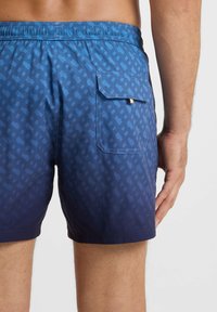 Swim shorts in blue gradient, featuring a textured geometric pattern. Elastic waistband and a back pocket with a gold accent.