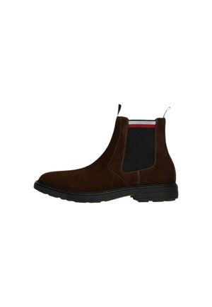Stivale Chelsea in suede marrone con pannello laterale elastico, dettagli neri, cuciture a contrasto e suola in gomma piatta. Presenta un tab di estrazione.