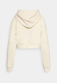 Sudadera corta de color beige con capucha ajustable, mangas largas y puños de canalé. Textura suave, diseño liso y sin adornos visibles.