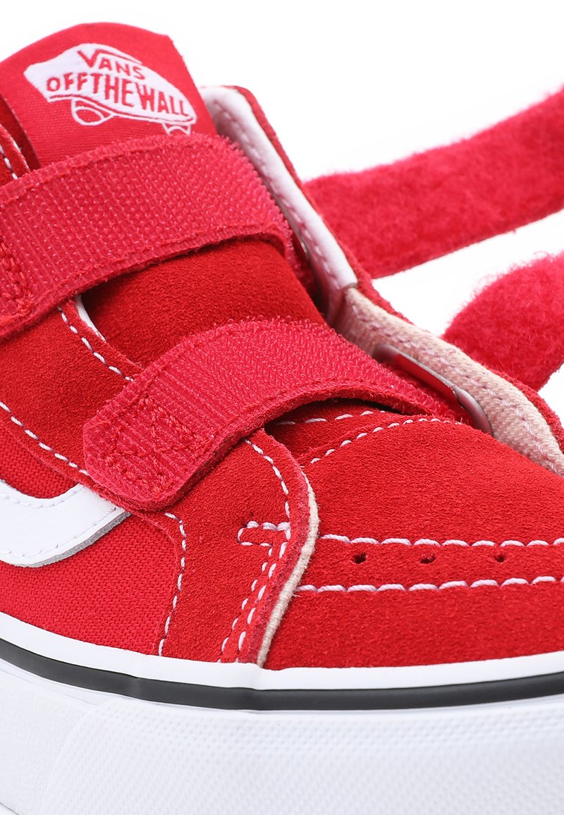 Baskets en daim rouge avec des accents blancs, dotées de straps Velcro ajustables, de détails cousus et d'une semelle en caoutchouc texturé.