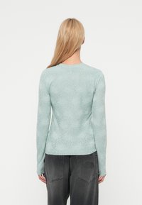 Ανοιχτό μπλε πουκάμισο με μακριά μανίκια και ανθικό σχέδιο, με στρογγυλή λαιμόκοψη, συνδυασμένο με σκούρο γκρι άνετο παντελόνι.