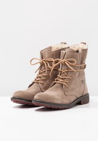Brune ruskind ankelstøvler med en tekstureret finish, rund tå, snørebåndsdesign og en polstret inderside for varme. Flad gummisål.