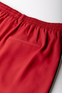 Röda shorts i mjuk tyg med elastisk midja och en liten, horisontell ficka på baksidan, med en enkel design.