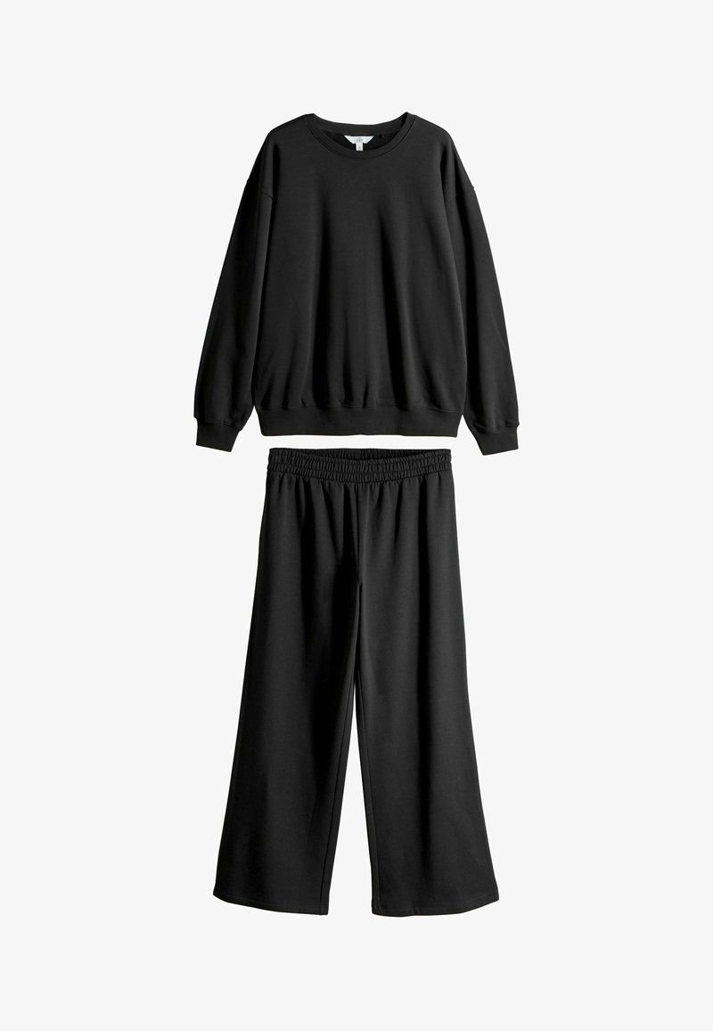 Čierne široké tepláky s elastickým pásom v kombinácii s dlhým rukávom mikinou. Obe vyrobené z mäkkého zmesi bavlny.