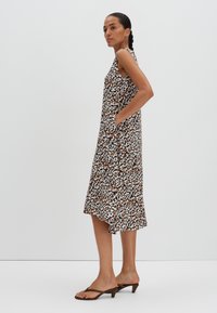 Mouwloze jurk met bloemenprint in bruin, wit en zwart. Beschikt over zijzakken en een gelaagde zoom. Lichtgewicht stof met een comfortabele fit.