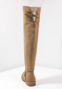 Tan suede over-the-knee boot with a fold-over cuff, side buckle detail, and a textured surface. Light brown rubber sole.