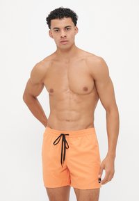 Șorturi de înot portocalii cu șnur negru și patch cu logo pe lateral. Fabricate dintr-un material ușor, acestea au o siluetă clasică și o textură netedă.