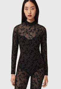 Black long-sleeve bodysuit with sheer floral embroidery, featuring a high neckline and fitted silhouette, highlighting intricate textured patterns.