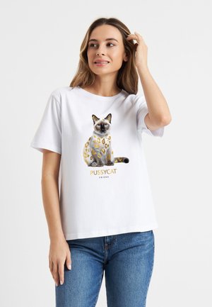 Witte katoenen t-shirt met een geprinte afbeelding van een Siamees kat met gouden en bruine accenten, en de tekst "PUSSYCAT FRIEDA" eronder.