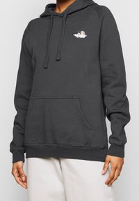 Sudadera de algodón gris oscuro con cordón ajustable, bolsillo frontal y diseño bordado en el pecho. Textura suave, puños y dobladillo acanalados.