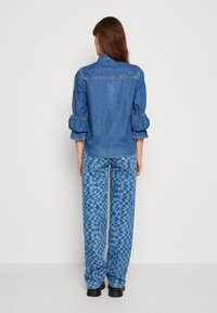 Jeansskjorta med puffärmar, ljusblå färg och sömdetaljer bak. I kombination med mönstrade blå vida jeans med geometriska mönster.