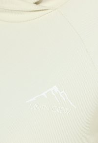 Helles cremefarbenes Sweatshirt mit Rippstruktur und Kapuze, versehen mit einem weißen Berg-Logo und dem Text "MNTN CREW" in moderner Schriftart.