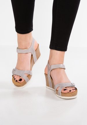 Gray wedge sandals with textured straps, cork heel, and white outsole; features adjustable ankle strap and silver hardware detail.