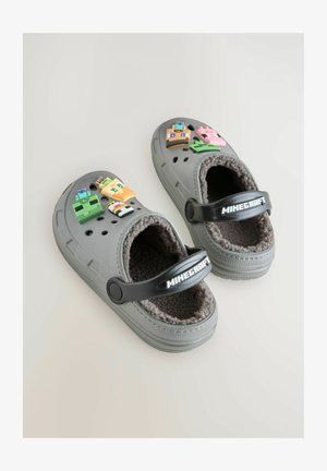 Graue Schlupfschläppchen mit einem flauschigen Innenfutter, versehen mit bunten Minecraft-Charakterabzeichen auf der Vorderseite und einem schwarzen verstellbaren Riemen.