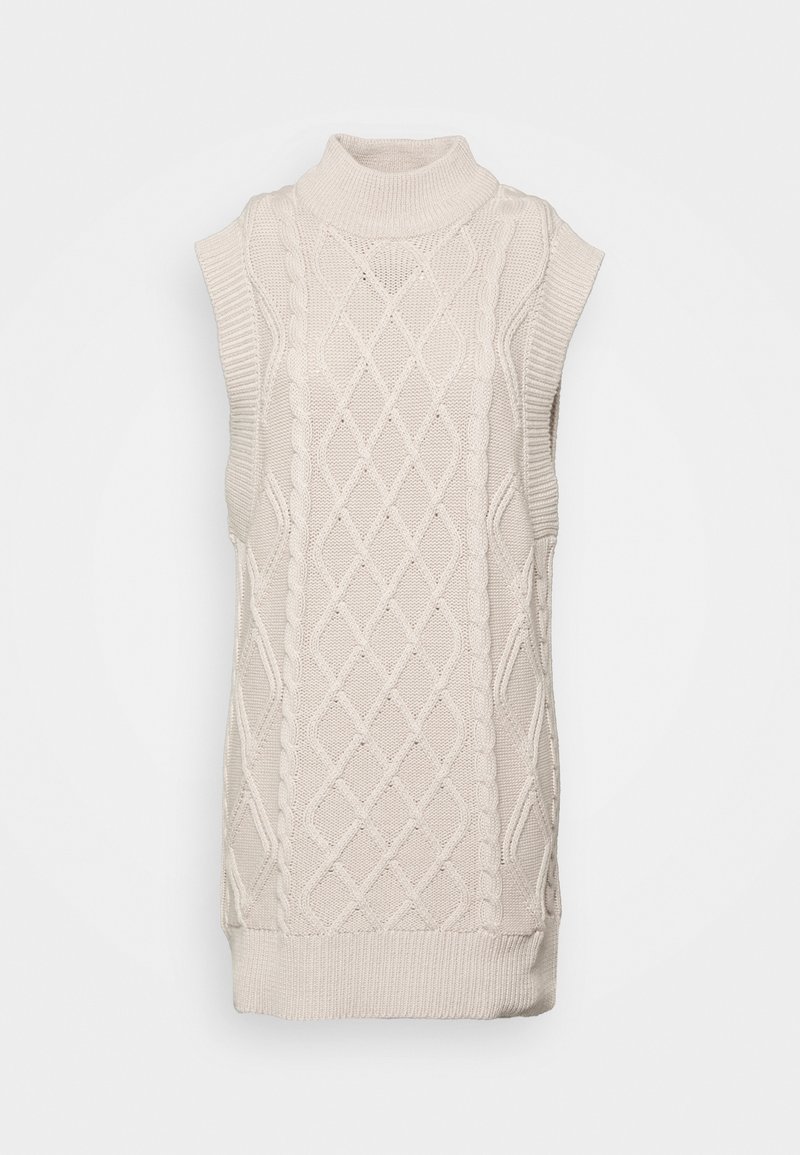 Robe-pull sans manches crème en maille avec col montant et motifs torsadés et losanges, présentée sur un fond uni.