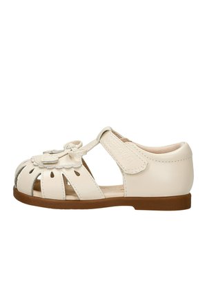 Kremowy sandał dla malucha z zamkniętym obcasem, otwartymi wycięciami na palce, ozdobą w kształcie kwiatu oraz regulowanym paskiem na rzep na brązowej podeszwie.