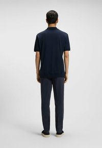 Marynarska koszulka polo z krótkim rękawem, z żebrowanym kołnierzykiem i dopasowanymi granatowymi spodniami. Lekka tkanina o gładkiej strukturze; czarne buty.