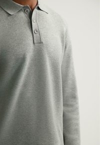 Lichtgrijze lange mouwen polo met een klassieke kraag en een sluiting met drie knopen, gemaakt van zachte stof.
