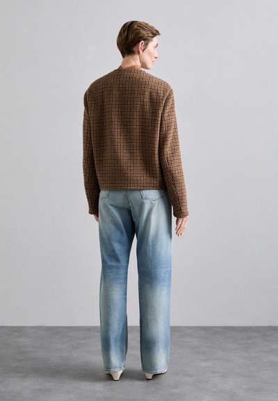 Brunternet strikket sweater med rund halsudskæring, parret med lys blå, blege straight-leg jeans og beige spidse hæle.