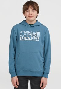 En gutt iført en blå O'Neill Santa Cruz hettegenser med frontlomme, står mot en ensfarget hvit bakgrunn.