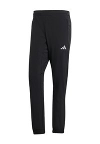 Pantalons de sport noirs à coupe fuselée, fabriqués en tissu lisse. Présentent des poches latérales et un logo réfléchissant sur la cuisse supérieure gauche.