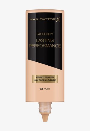 Max Factor Facefinity foundation i benvit, cylindrisk beige tube med svart etikett och gyllene accenter, har en munstycke för utfodring.