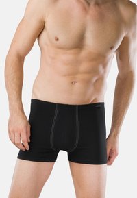 Czarne bokserki z elastycznym pasem, o gładkiej fakturze, z kontrastującym białym przeszyciem z przodu, dopasowany krój i długość do połowy uda.